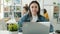 Portrait of call center worker sitting in modern workplace with headphones and laptop