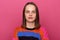 Portrait of calm cute attentive young adult Caucasian woman with brown hair wearing colorful jumper posing isolated over pink