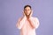 Portrait of calm young man covering ears with hands do not wanna listen standing on pink  background in studio