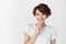 Portrait of candid happy woman smiling and touching chin, looking pensive, standing against white background