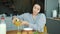 Portrait of carefree Asian woman pouring juice in glass during breakfast at home