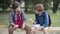 Portrait of carefree Caucasian schoolboys sitting on bench and eating sandwiches. Relaxed friends chatting during lunch