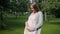 Portrait of carefree expecting mother standing in summer park touching belly smiling enjoying warm day and nature