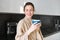 Portrait of carefree smiling woman drinking coffee, standing in kitchen with delighted, pleased face expression, waking