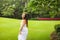 Portrait of carefree young woman in white dress posing in green summer park