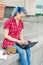 Portrait of a casual cute and young girl with blue hair in jeans in urban summer drawing or writing