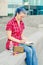 Portrait of a casual cute and young girl with blue hair in jeans in urban summer drawing or writing