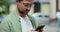 Portrait of casual man in glasses using smartphone on the street. Handsom bearded man typing messages on phone outside