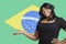 Portrait of casual mixed race woman holding out empty palm over Brazilian flag