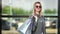 Portrait casual smiling blonde woman in stylish sunglasses posing with shopping bag