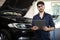 Portrait of caucasian bearded handsome man auto mechanic or manager in goggles smiling to camera in garage. Cheerful guy