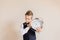 Portrait of caucasian Boy in grey suit with big clock.Cute boy holding and hearing Clock. Child back to school.Neutral background