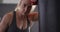 Portrait of caucasian female boxer leaning on punching bag at the gym
