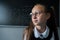 Portrait of a caucasian girl in glasses in the classroom. The schoolgirl answers at the blackboard.