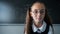 Portrait of a caucasian girl in glasses in the classroom. The schoolgirl answers at the blackboard.