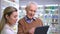Portrait of Caucasian grey-haired senior man talking with pharmacist in drugstore smiling. Positive satisfied client