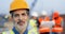 Portrait of Caucasian handsome middle-aged man constructor in casque standing outdoors at construction and looking at