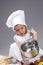 Portrait of Caucasian Little Girl In Cook Uniform Working With Scoop and Saucepan