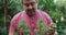 Portrait of caucasian male gardener holding bonsai tree at garden center