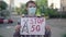 Portrait of Caucasian man with Stop 5G banner standing on urban city street. Serious male demonstrator in face mask