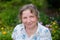 Portrait of caucasian mature cheerful mature woman standing outdoors in garden. She is smiling.