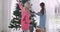 Portrait of Caucasian mother and daughter decorating Christmas tree at home. Family preparing for holidays season