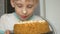 Portrait of Caucasian preschooler boy licks cake. The child eats dessert, having smeared his face with sweet protein cream. Humor