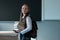 Portrait of a caucasian schoolgirl with a backpack. The girl is holding a stack of textbooks in the classroom.