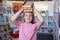 Portrait of caucasian schoolgirl smiling carrying stack of books on head in school library