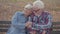 Portrait of a Caucasian senior couple sitting on the bench and talking. Mature husband calming down his beautiful senior