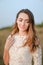 Portrait of caucasian smiling bride standing in steppe and wearing white dress.