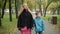Portrait of Caucasian woman and boy walking in autumn park holding hands talking and leaving. Happy joyful mother and