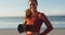 Portrait of caucasian woman holding yoga mat at the beach smiling