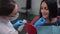 Portrait of Caucasian woman looking at hand mirror as dentist trying on implant. Close-up female patient and dentist