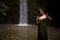 Portrait of Caucasian woman near the waterfall. Enjoy nature. Water splash. Young woman wearing green dress. Travel to Asia. Copy