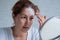 Portrait of a Caucasian woman with vitiligo uses sunscreen. A girl with a white pigment spot on her forehead looks in