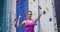 Portrait of caucasian woman wearing harness and holding ropes at indoor climbing wall
