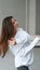 Portrait of a caucasian young dreamy brunette with windswept hair. Tender woman in white shirt vertical photo