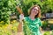 Portrait of caucasian young woman with a smile holds a bunch of carrots collected from the garden.Vegetation in the background.