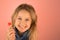 Portrait of charming angelic beautiful blonde school girl 9 years old holds red candy in her hand, pink background, close-up, copy