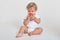 Portrait of charming baby boy posing with red apple, trying bite it, playing indoor isolated over white background, looking away,