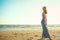 Portrait of a charming blond long-haired woman walking along the seaside, her wavy hair blown by the wind