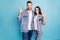 Portrait of charming couple making okay sign wearing denim jeans isolated over blue background