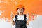 Portrait of a charming girl in an orange hard hat on her head. raised index fingers upward emotion of surprise.