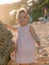 Portrait of charming girl in pink dress on ocean beach with sunset light