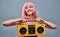 Portrait of charming half naked woman in pink wig holding old vintage boombox isolated over grey background