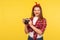 Portrait of charming happy pinup girl in checkered shirt and headband holding old fashioned camera and smiling