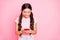 Portrait of charming kid holding device looking searching news wearing white t-shirt  over pink background