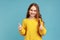 Portrait of charming little girl with wavy hair showing thumbs up to camera, expressing positive.