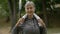 Portrait of the charming mature woman in sporty clothes carrying towel in her neck. Elderly female looking at camera